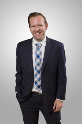 A man in suit and tie smiling for the camera.