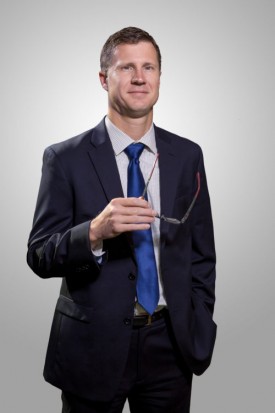 A man in suit and tie holding glasses.