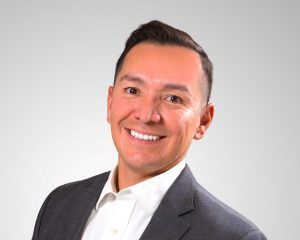 A man in a suit and tie smiling for the camera.