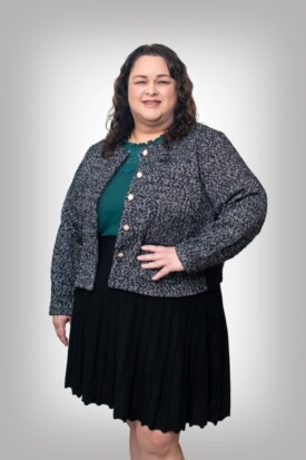 A woman standing in front of a gray background.